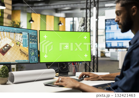 Middle eastern contractor prepares apartment floor plan next to copy space monitor, decorating and designing the new construction building layout. 3D software for interior design. 132421463