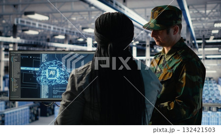 Military staff in server room uses AI tools to help manage computer systems. Army team wearing uniform reviews information using artificial intelligence programs in server farm, camera B Military staff in server room uses AI tools to help manage computer systems. Army team wearing uniform reviews information using artificial intelligence programs in server farm, camera B 132421503