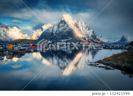 Snowy mountains reflect in fjord under dramatic clouds at sunset 132421599