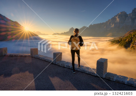 Woman standing above clouds at sunset in the Swiss Alps 132421603