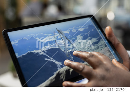 Close up of technician using touchscreen tablet to evaluate next generation wind turbine boosting green energy output. Product designer develops cutting edge vertical axis wind turbine using device 132421704