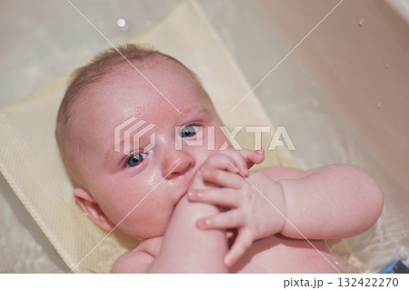 Infant baby boy washed in small bath tub, view from above 132422270