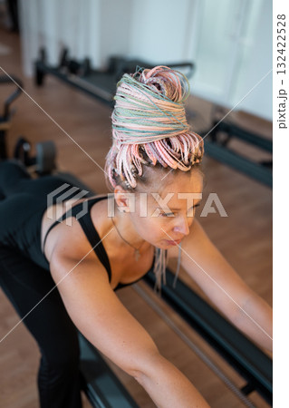 Woman training pilates on the reformer bed. Reformer pilates studio machine for fitness workouts in gym. Fit, healthy and strong authentical body. Fitness concept Woman training pilates on the reformer bed. Reformer pilates studio machine for fitness workouts in gym. Fit, healthy and strong authentical body. Fitness concept 132422528