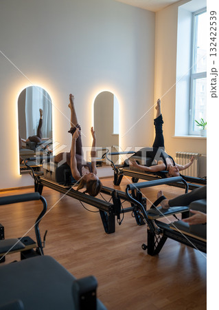 Studio reformer class dynamics, energetic group pilates reformer session with focused movement 132422539