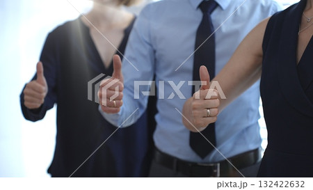 Business people team showing thumbs up gestures in a row, expressing approval, agreement, success, and full support for a project or strategy in a corporate office setting with sun flair 132422632
