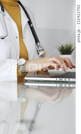 Female doctor working on laptop, managing patient data, writing prescriptions in clinic and filling out patient medical records. Concept of medicine, healthcare and science Female doctor working on laptop, managing patient data, writing prescriptions in clinic and filling out patient medical records. Concept of medicine, healthcare and science 132422702