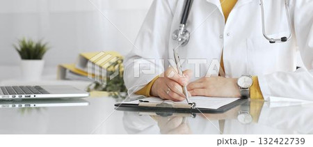 Female physician or medic completing paperwork, preparing a diagnosis, or providing healthcare service in a clean modern office. Medicine, healthcare and science concept Female physician or medic completing paperwork, preparing a diagnosis, or providing healthcare service in a clean modern office. Medicine, healthcare and science concept 132422739