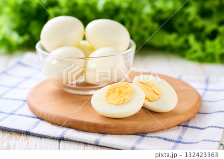 boiled chicken eggs peeled and cut in half on a white table, selective focus. boiled chicken eggs peeled and cut in half on a white table, selective focus. 132423363
