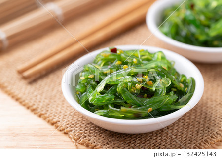 Wakame seaweed salad with sesame seed in a bowl with chopsticks 132425143