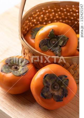 Ripe persimmon fruit in basket on wooden background, Autumn fruit Ripe persimmon fruit in basket on wooden background, Autumn fruit 132425147