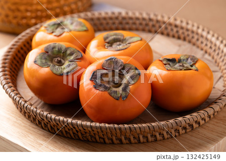 Ripe persimmon fruit in basket on wooden background, Autumn fruit 132425149