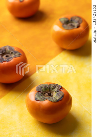 Ripe persimmon fruit on orange with yellow color background, Autumn fruit 132425152