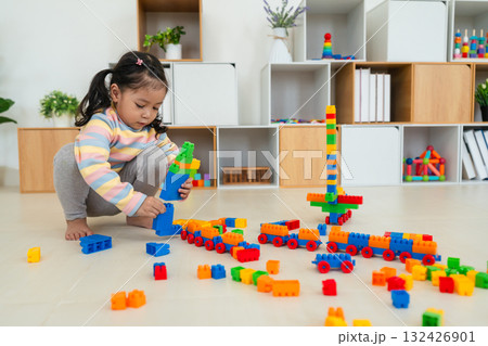 toddler girl playing building blocks or plastic bricks toy at home 132426901