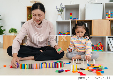 toddler girl and mother playing colorful wooden block toy or domino game together toddler girl and mother playing colorful wooden block toy or domino game together 132426911