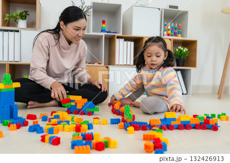 happy toddler girl and mother playing building blocks or plastic bricks toy at home 132426913