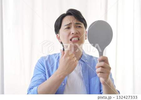 鏡を見る虫歯に悩む男性　20代 132427333