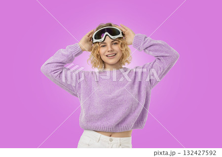 Cheerful woman in ski goggles and a purple sweater 132427592