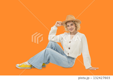 Woman with curly hair wearing a sweater and hat poses casually Woman with curly hair wearing a sweater and hat poses casually 132427603