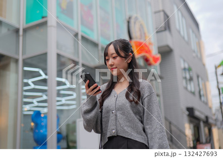 スマートフォンを見ながら原宿の路地を歩く若い女性 132427693
