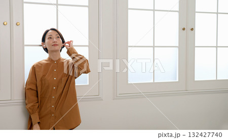 窓際で音楽やラジオを聴いている女性 窓際で音楽やラジオを聴いている女性 132427740