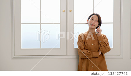 窓際で音楽やラジオを聴いている女性 窓際で音楽やラジオを聴いている女性 132427741