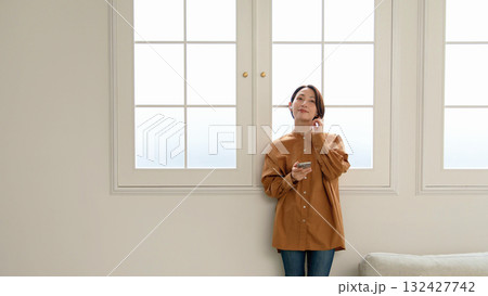 窓際で音楽やラジオを聴いている女性 窓際で音楽やラジオを聴いている女性 132427742
