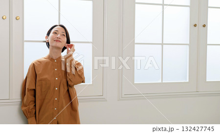 窓際で音楽やラジオを聴いている女性 窓際で音楽やラジオを聴いている女性 132427745