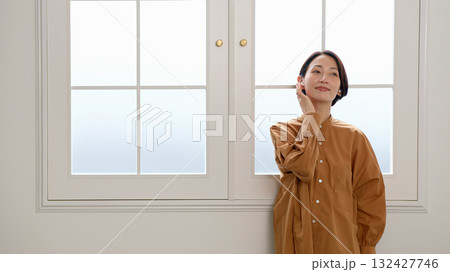 窓際で音楽やラジオを聴いている女性 132427746
