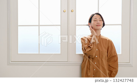 窓際で音楽やラジオを聴いている女性 132427748