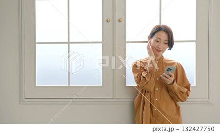 窓際で音楽やラジオを聴いている女性 132427750