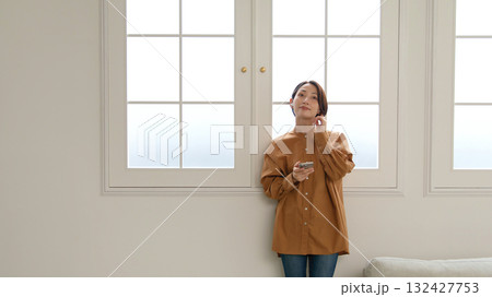 窓際で音楽やラジオを聴いている女性 132427753