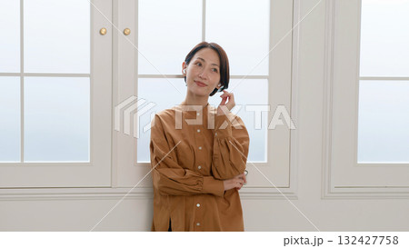 窓際で音楽やラジオを聴いている女性 132427758