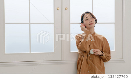 窓際で音楽やラジオを聴いている女性 132427760