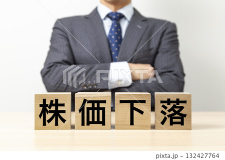 「株価下落」と書かれたブロックと腕組みをするビジネスマン 132427764