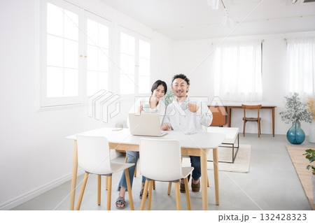 綺麗なリビングでダイニングカメラ目線の夫婦　幸せな結婚のイメージ全身の広角 132428323