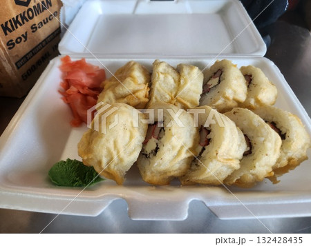 Delicious Sushi Rolls With Drizzled Sauce, Pickled Ginger, and Wasabi in Takeout Box 132428435