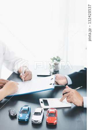 Businessman explaining car loan agreement with calculator, customer discussing auto finance deal at office desk with toy car and document, concept of vehicle loan, insurance or car leasing. car loan. Businessman explaining car loan agreement with calculator, customer discussing auto finance deal at office desk with toy car and document, concept of vehicle loan, insurance or car leasing. car loan. 132428537