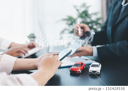 Car loan officer explaining contract details to customer with cash, calculator, key and toy car on table, concept of auto finance, leasing, insurance, payment plan and business agreement. car loan. 132428538