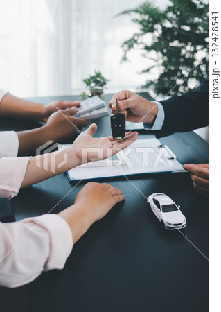 Customer receiving car key from dealer after signing contract, successful auto purchase and finance agreement at office desk, concept of vehicle loan, leasing, insurance or ownership. vehicle loan. Customer receiving car key from dealer after signing contract, successful auto purchase and finance agreement at office desk, concept of vehicle loan, leasing, insurance or ownership. vehicle loan. 132428541