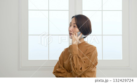 窓際で電話をしている女性 窓際で電話をしている女性 132429724