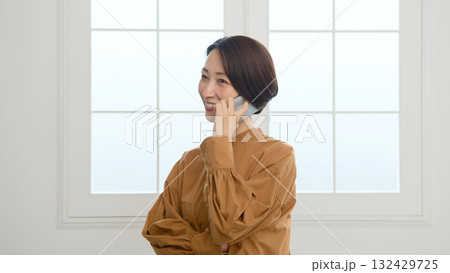 窓際で電話をしている女性 窓際で電話をしている女性 132429725