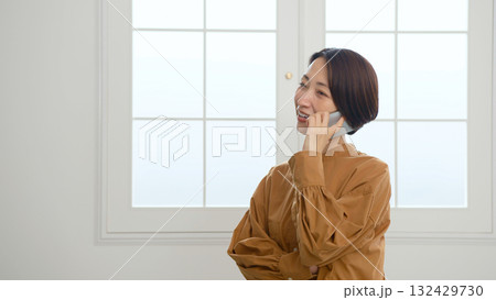 窓際で電話をしている女性 窓際で電話をしている女性 132429730