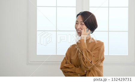 窓際で電話をしている女性 窓際で電話をしている女性 132429731