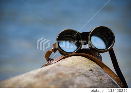 Binoculars Resting on Rock by the Sea, Outdoor Adventure Gear for Exploration and Discovery Binoculars Resting on Rock by the Sea, Outdoor Adventure Gear for Exploration and Discovery 132430233