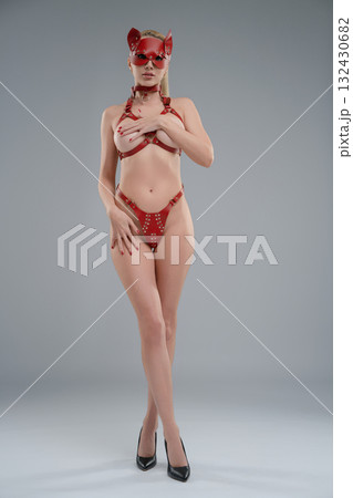 Woman poses confidently in leather belts in modern studio setting Woman poses confidently in leather belts in modern studio setting 132430682