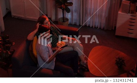 Happy father and mother watching TV together while eating snack. Convocation. 132431741