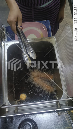 Street food fryer hot oil deep frying tongs hand night crispy snack with lively vibe 132431824