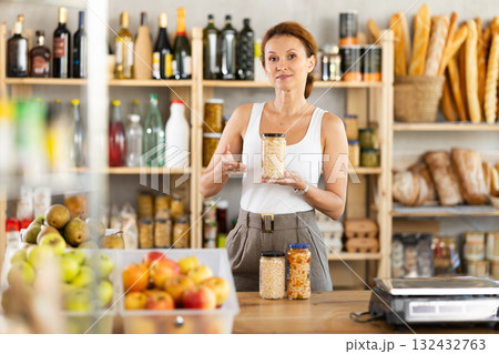 Adult woman seller offers beans in grocery store 132432763