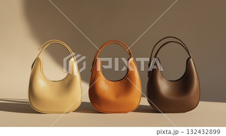 Soft yellow orange brown leather handbag trio on neutral background evoking warm elegant mood 132432899