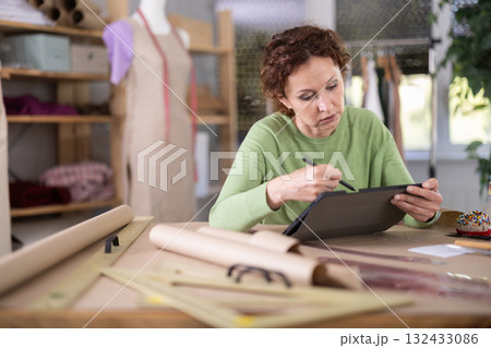 Female dressmaker working on digital sketch of dress in workshop Female dressmaker working on digital sketch of dress in workshop 132433086